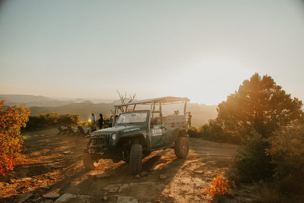 An off-road vehicle parked on a rocky path with sunset views in the background.