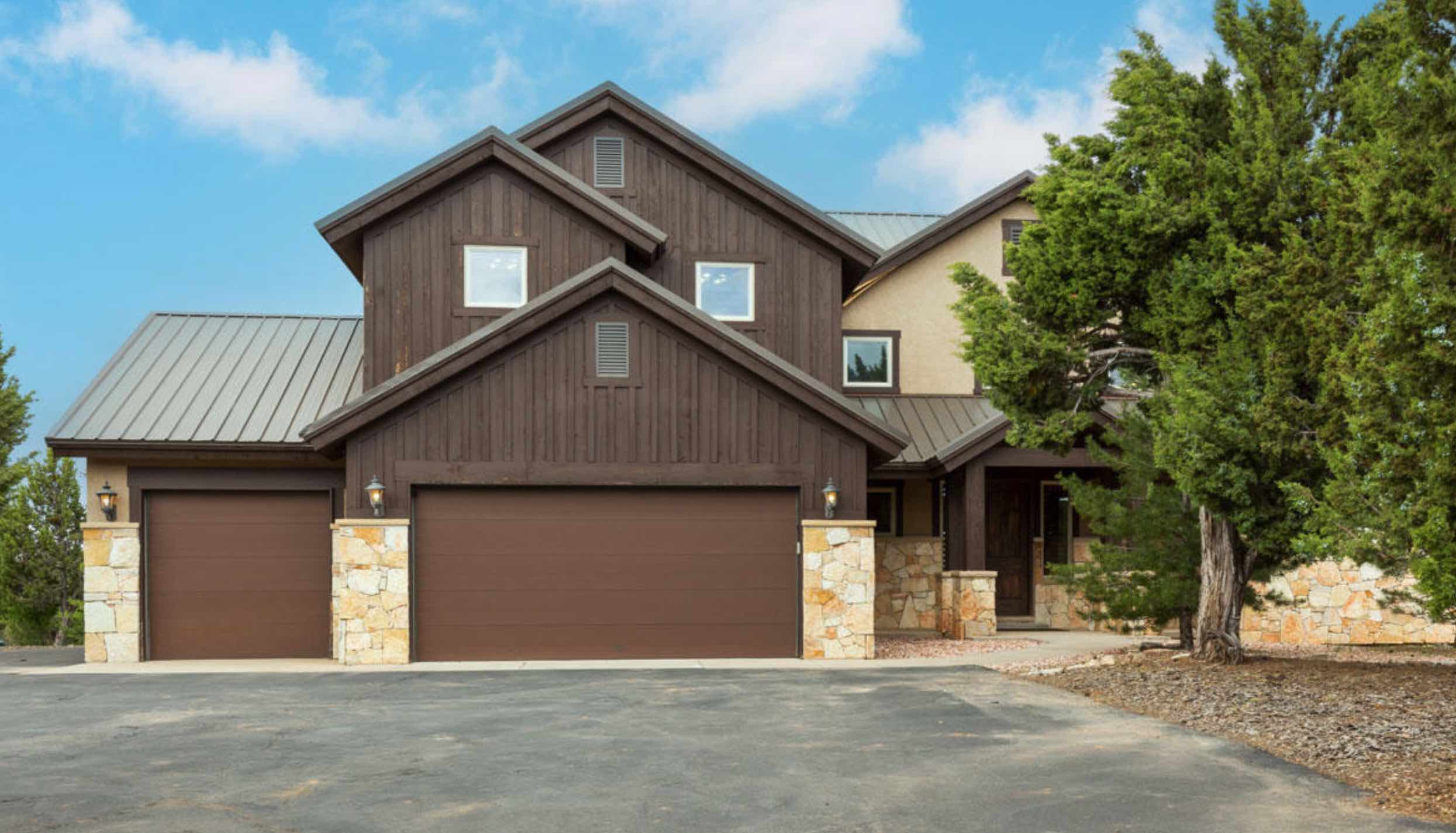 A modern two-story house with a combination of dark wooden siding and stone accents.