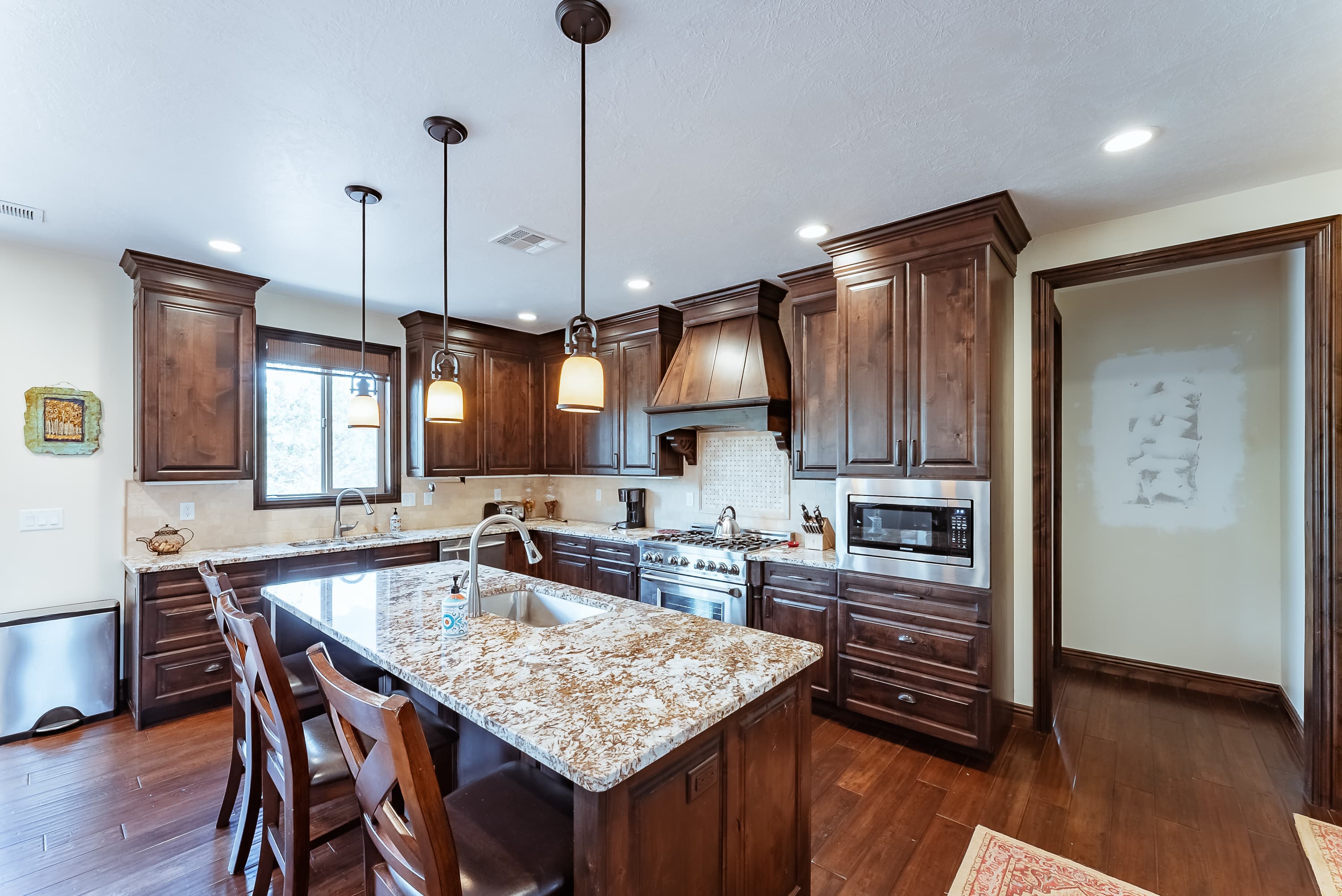 Modern kitchen featuring dark wood cabinets, granite countertops, and a central island with seating.