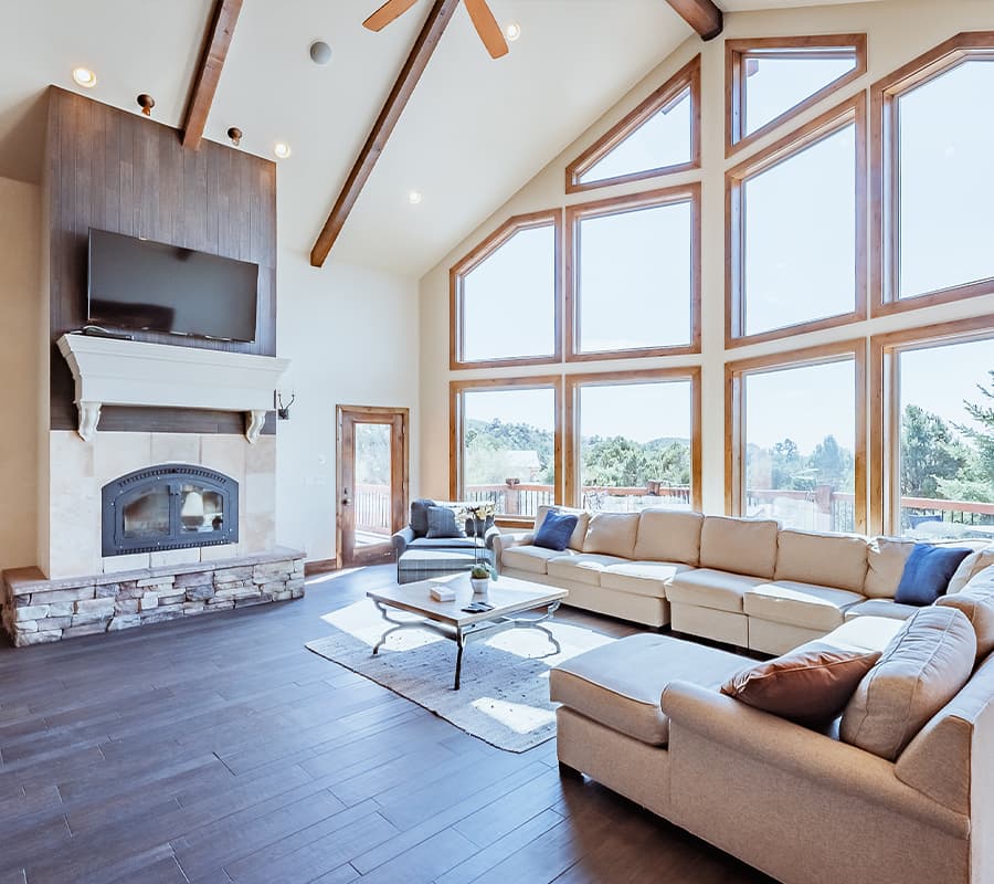 Spacious living room with large windows, a cozy fireplace, and stylish furnishings.