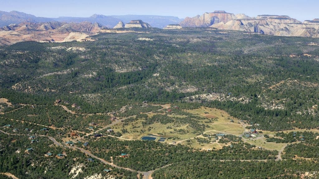 Aerial view of a lush valley surrounded by rugged mountains and scattered buildings.