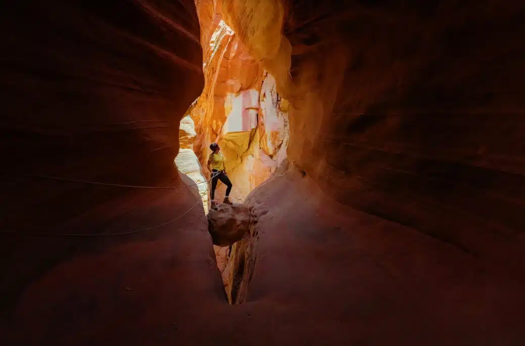 A person stands in a narrow, brightly lit canyon.