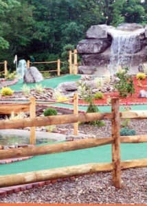 A mini-golf course featuring a rocky waterfall and lush greenery.