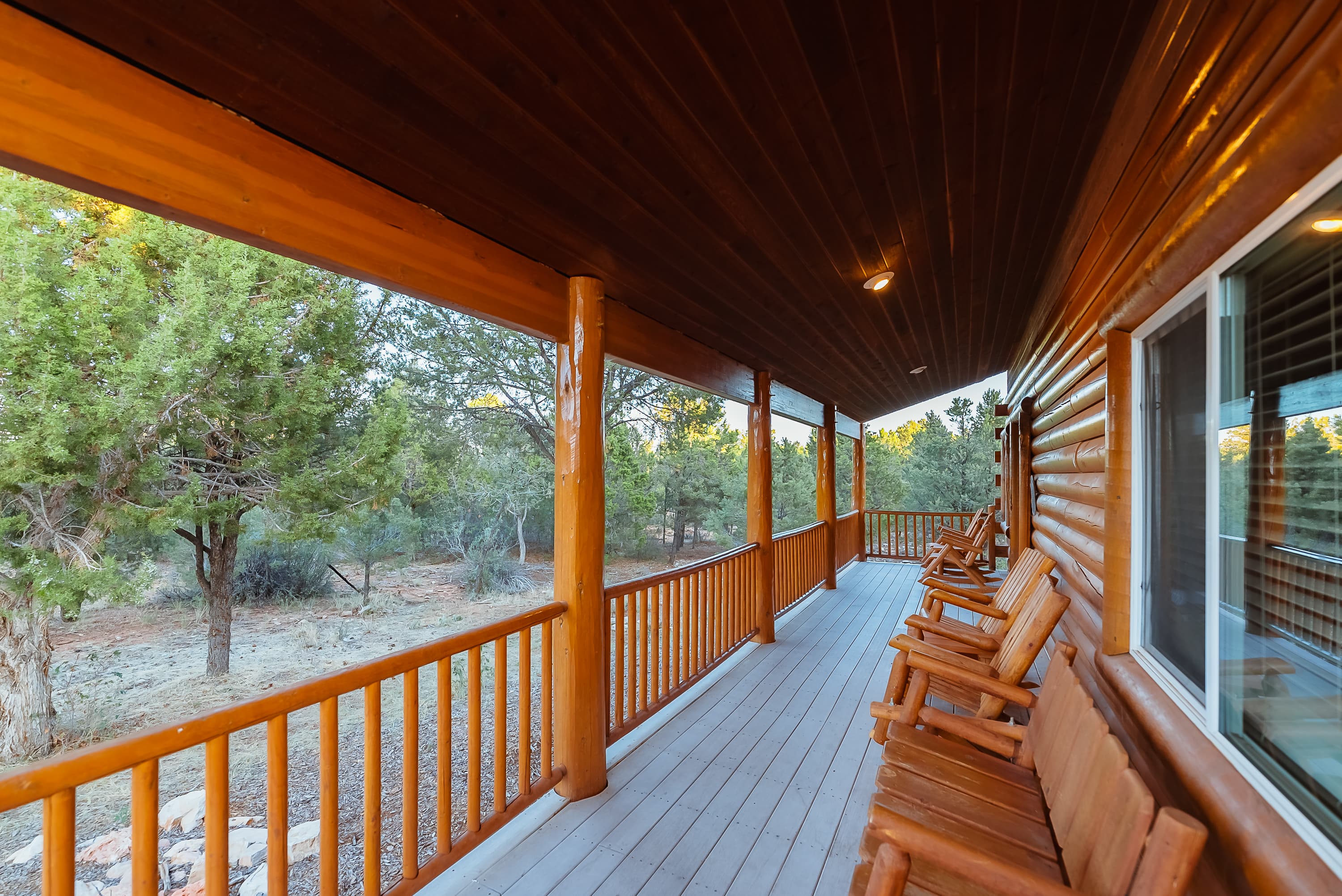 A wooden porch with rocking chairs overlooks a natural landscape.