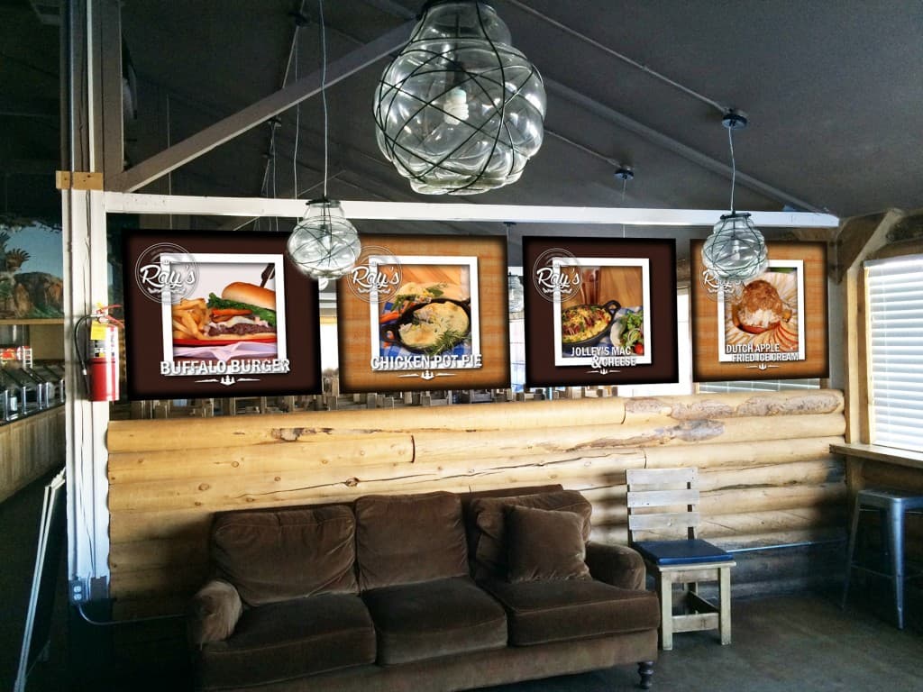 A cozy dining area featuring a sofa and illuminated menu boards displaying various food items.