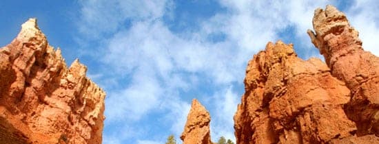 Towering red rock formations against a blue sky with scattered clouds.