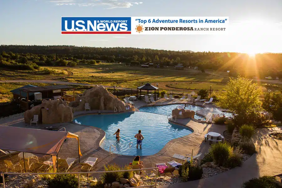 A scenic view of a resort pool surrounded by picturesque landscapes at sunset.