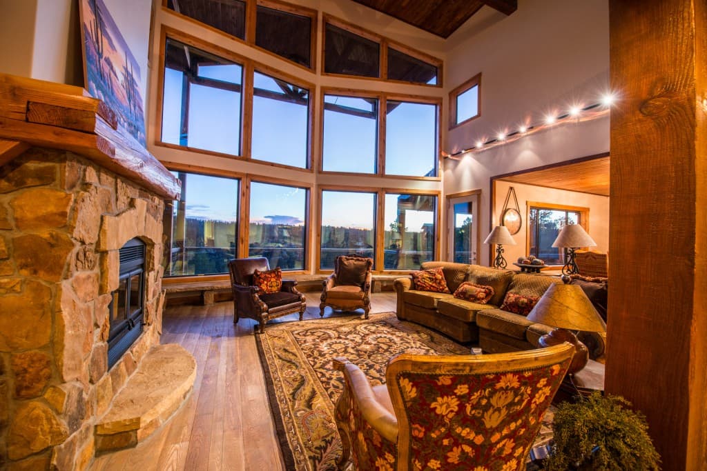 A cozy living room featuring large windows with scenic views, a stone fireplace, and comfortable seating.