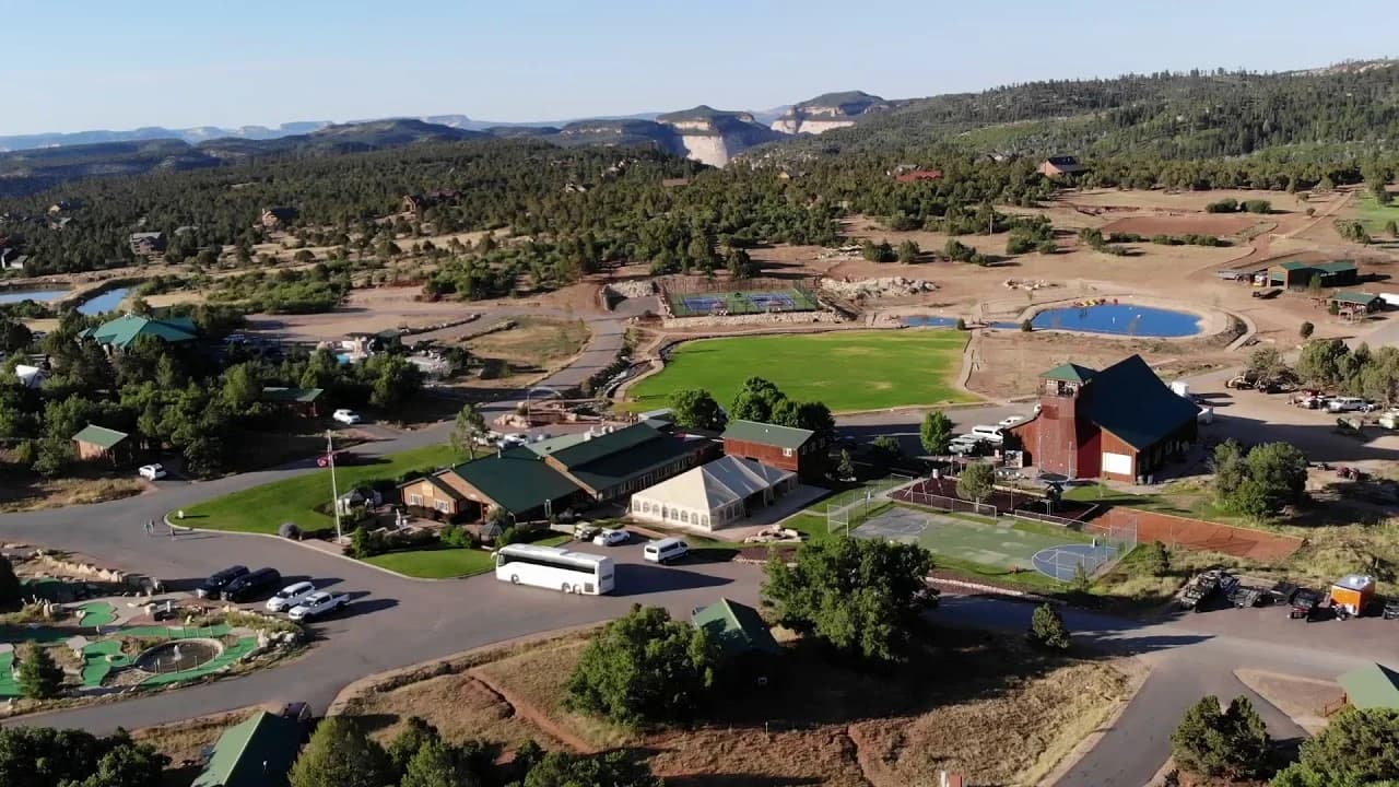 Aerial view of a facility surrounded by greenery, featuring sports fields and buildings.