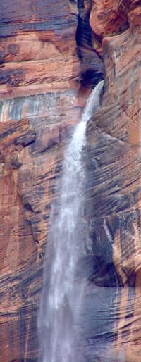 A waterfall cascades down a rugged rock face.