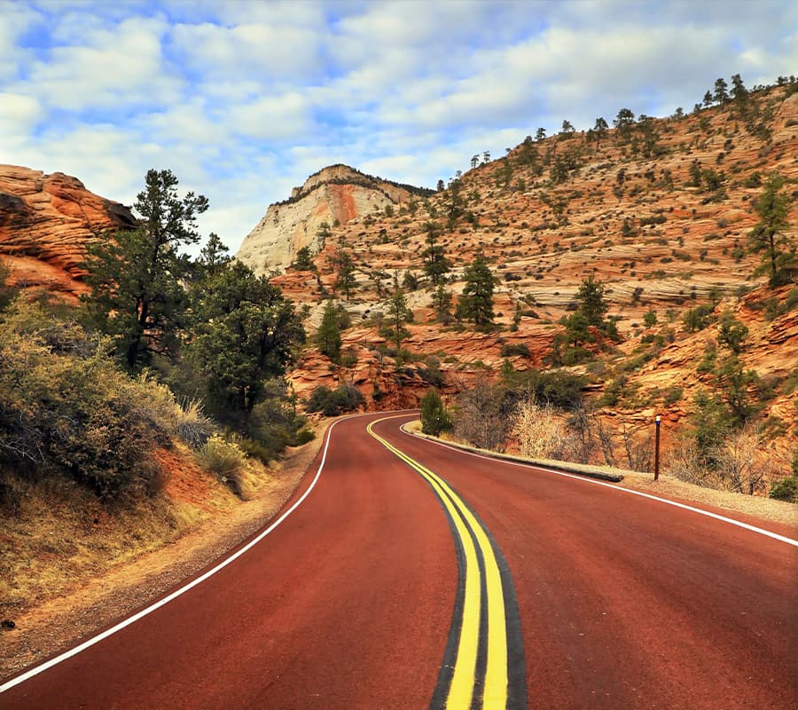 Winding road through rocky terrain under a cloudy sky.