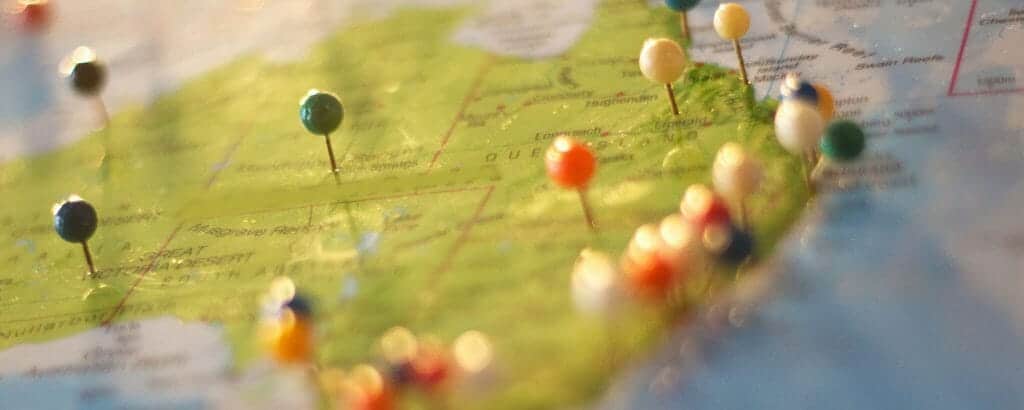 A close-up of a map marked with colorful pins.
