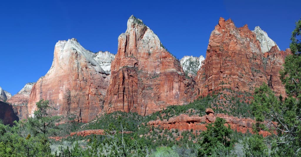 Majestic red rock formations rise against a clear blue sky in Zion National Park.