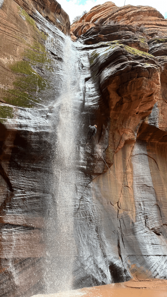 A waterfall cascades down a smooth, steep rock face.