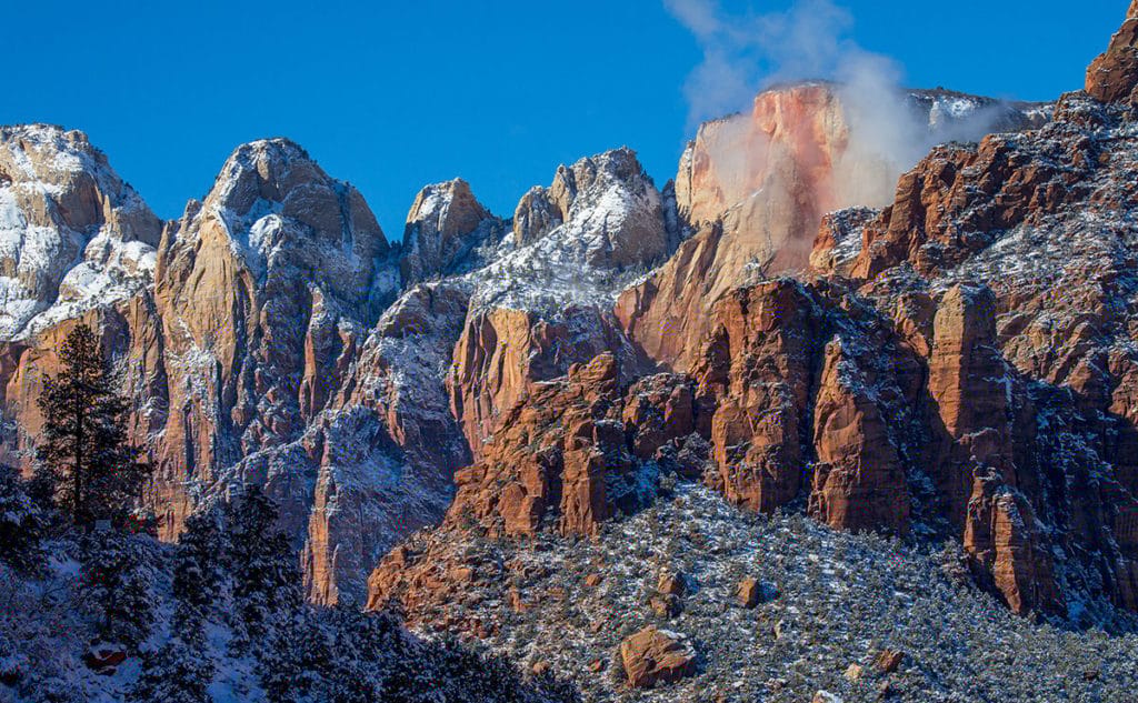 Snow-capped red rock formations under a clear blue sky.