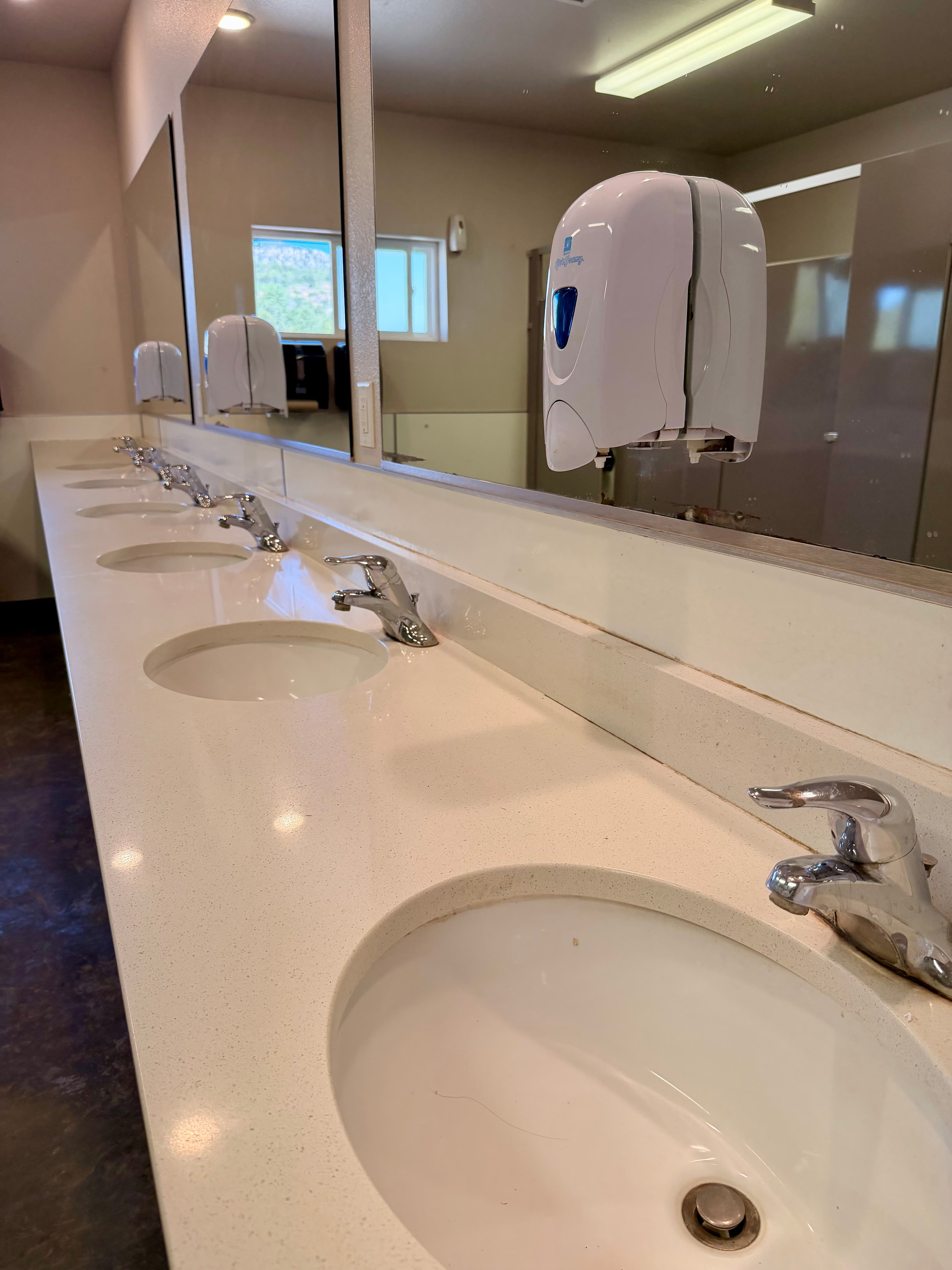 A public restroom with multiple sinks and a hand dryer.