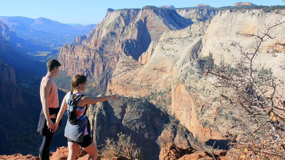 A couple stands at the edge of a canyon, gazing at the stunning landscape below.