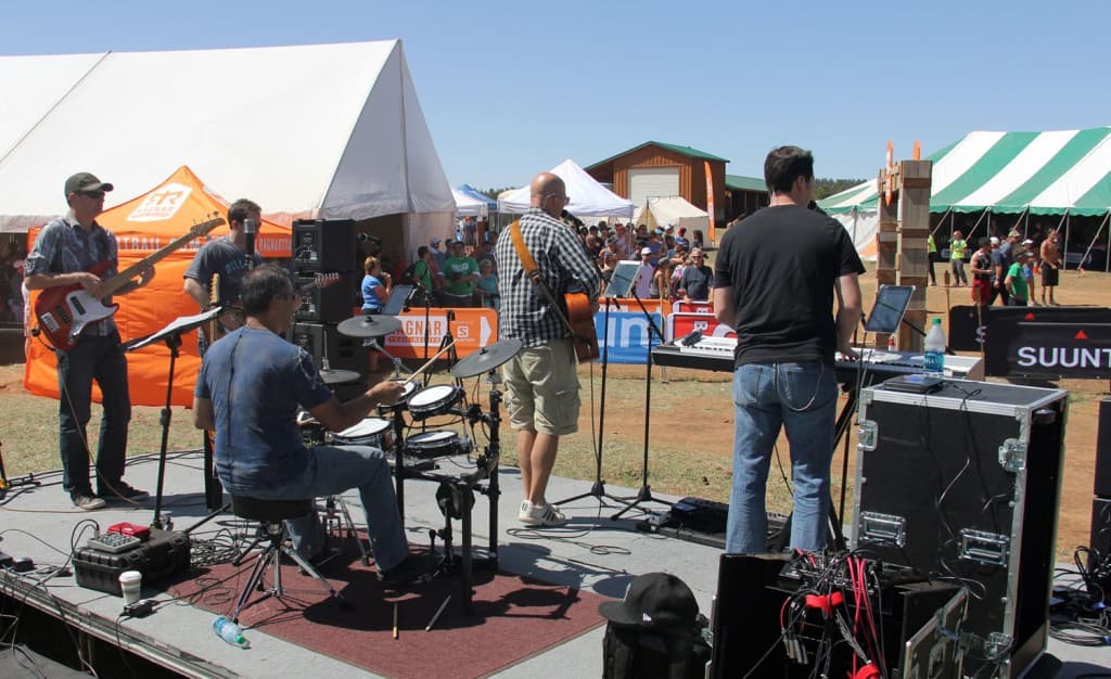 A band performs on stage in front of an audience at an outdoor festival.