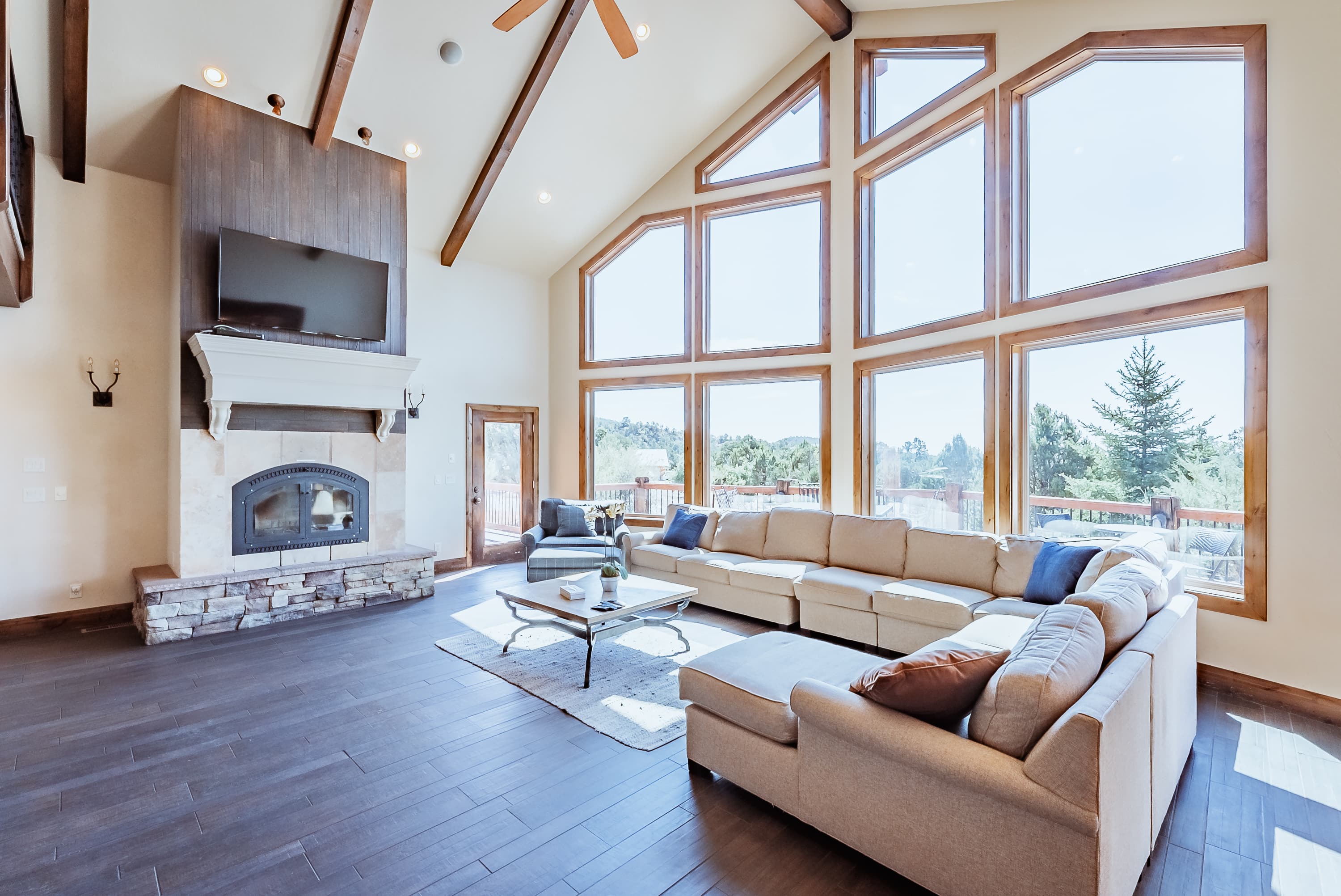 Spacious living room featuring a large sectional sofa, stone fireplace, and expansive windows for natural light.