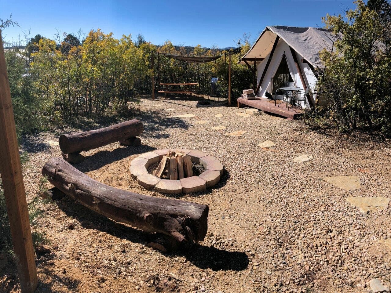 Cozy outdoor campsite featuring a fire pit surrounded by logs and a tent.