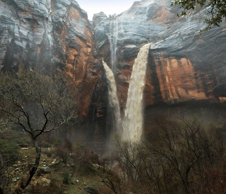 A stunning view of a double waterfall cascading down rocky cliffs surrounded by trees.