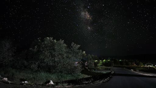 A starry night sky filled with stars and the Milky Way over a dark landscape.