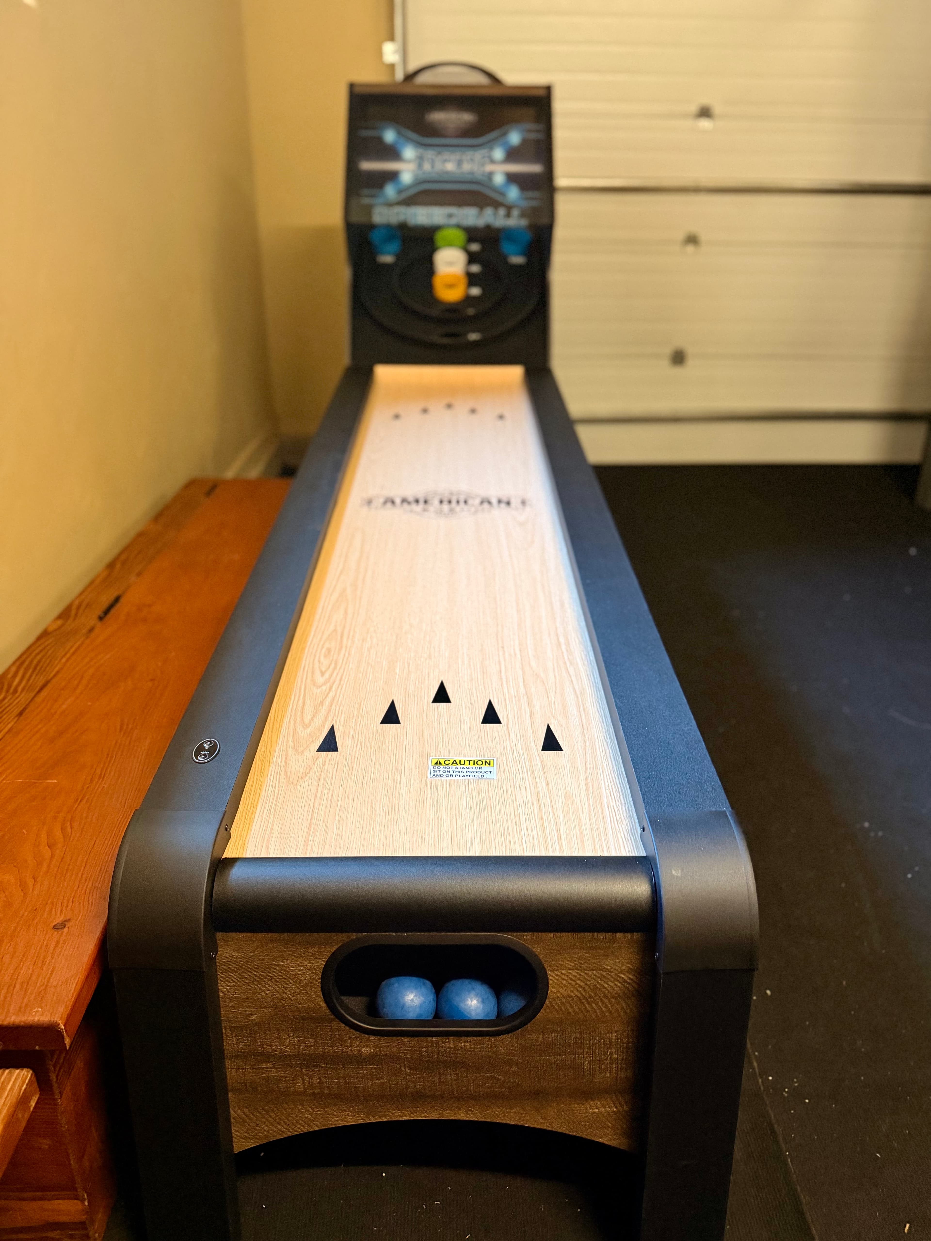 A bowling lane game with a wooden surface and a control panel at the back.