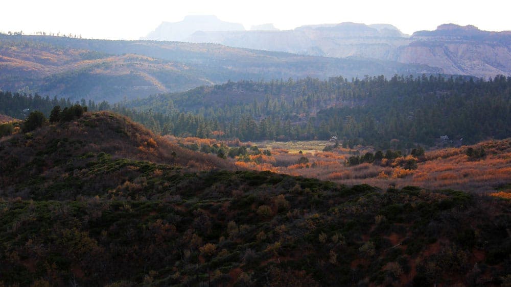 A panoramic view of layered hills and valleys under soft, diffused light.