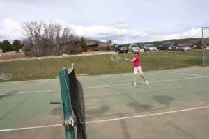 A player in a pink shirt swings a tennis racket on an outdoor court.