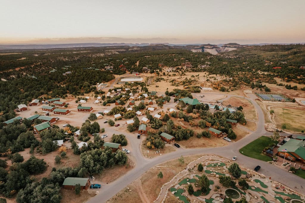 Aerial view of a rustic lodge area surrounded by trees and hills.