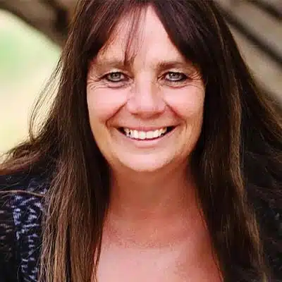 A woman with long brown hair smiles warmly at the camera.