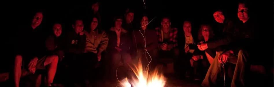 A group of people gathered around a campfire at night.