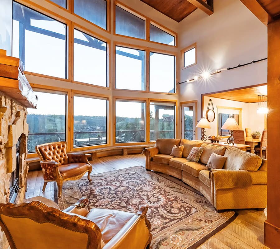 A cozy living room featuring large windows with scenic views, a plush sofa, and elegant decor.