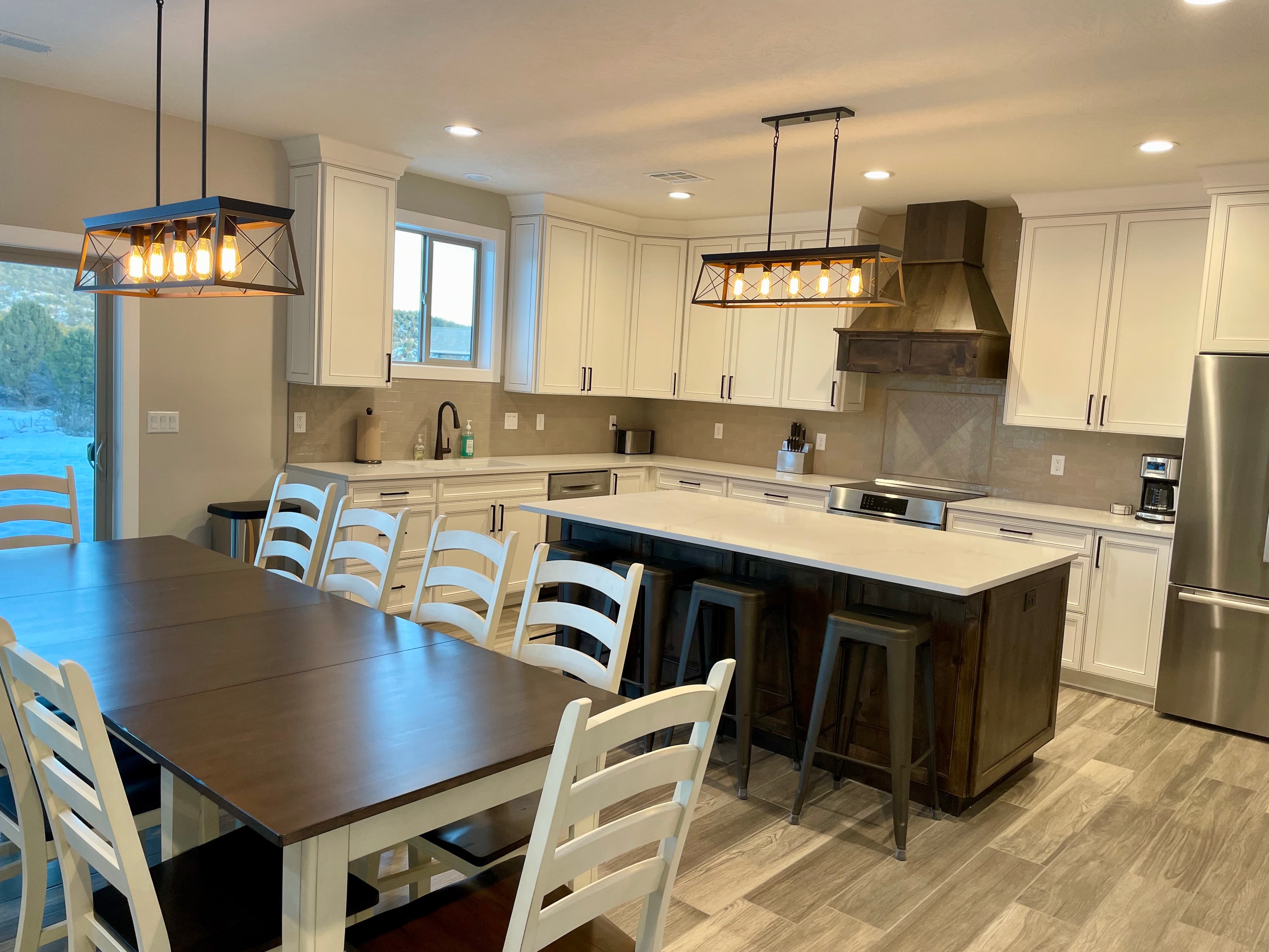 A modern kitchen with white cabinets, a central island, and a large dining table.