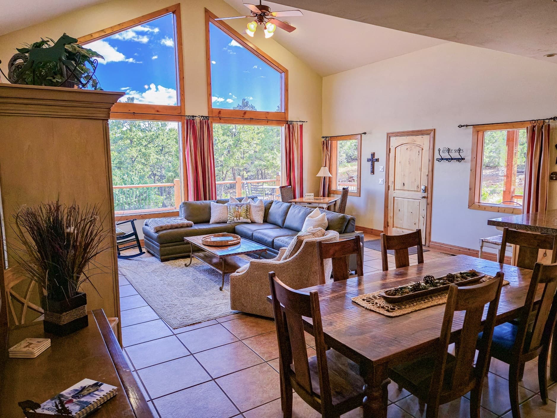 A cozy living room with large windows, a sectional sofa, and a dining table.