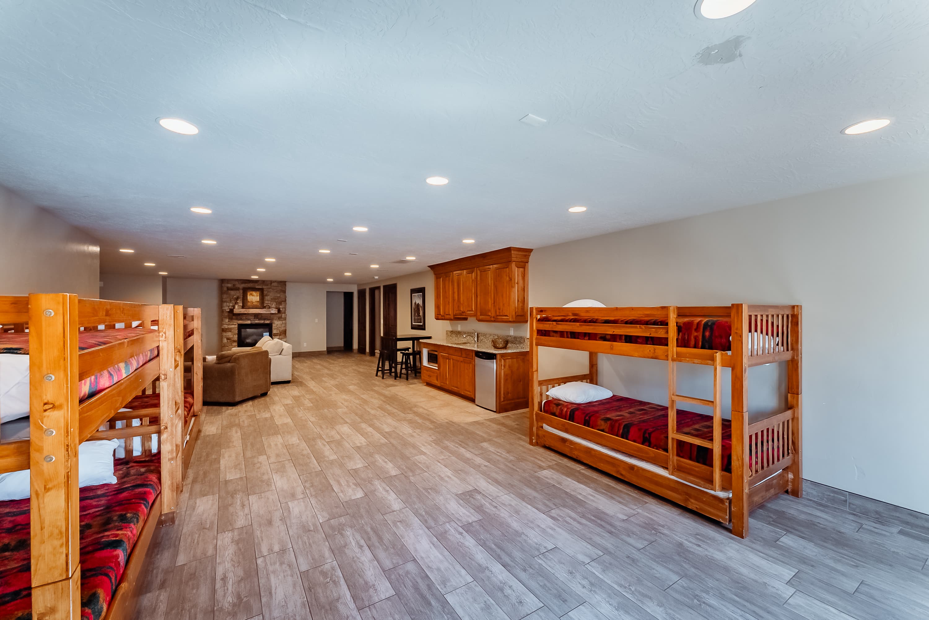 A spacious room featuring wooden bunk beds, a cozy seating area, and a kitchenette.