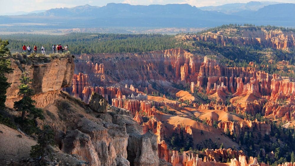 A group of hikers stands on a cliff overlooking the colorful formations of Bryce Canyon.