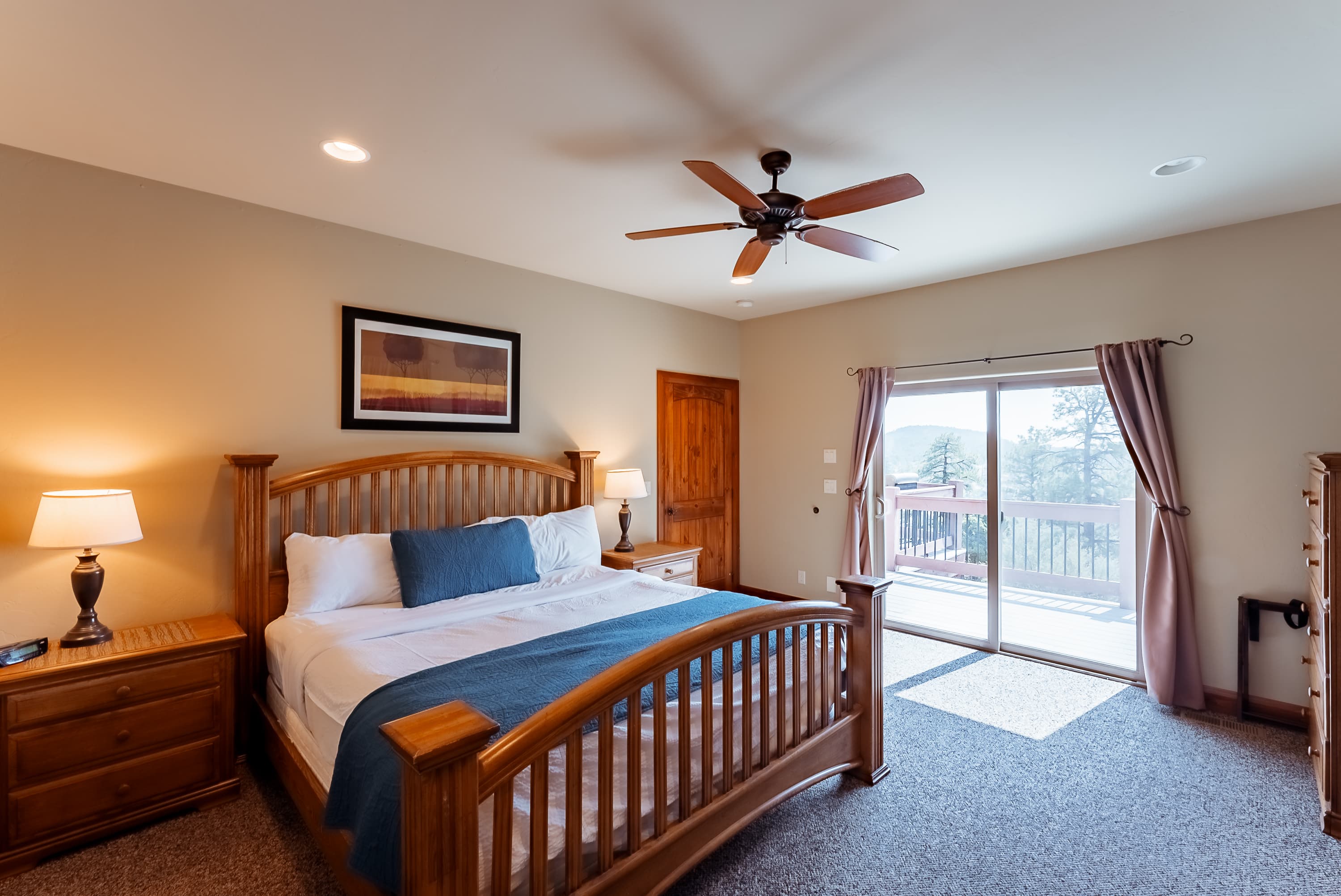 A cozy bedroom with a wooden bed, two lamps, and a sliding door leading to a balcony.