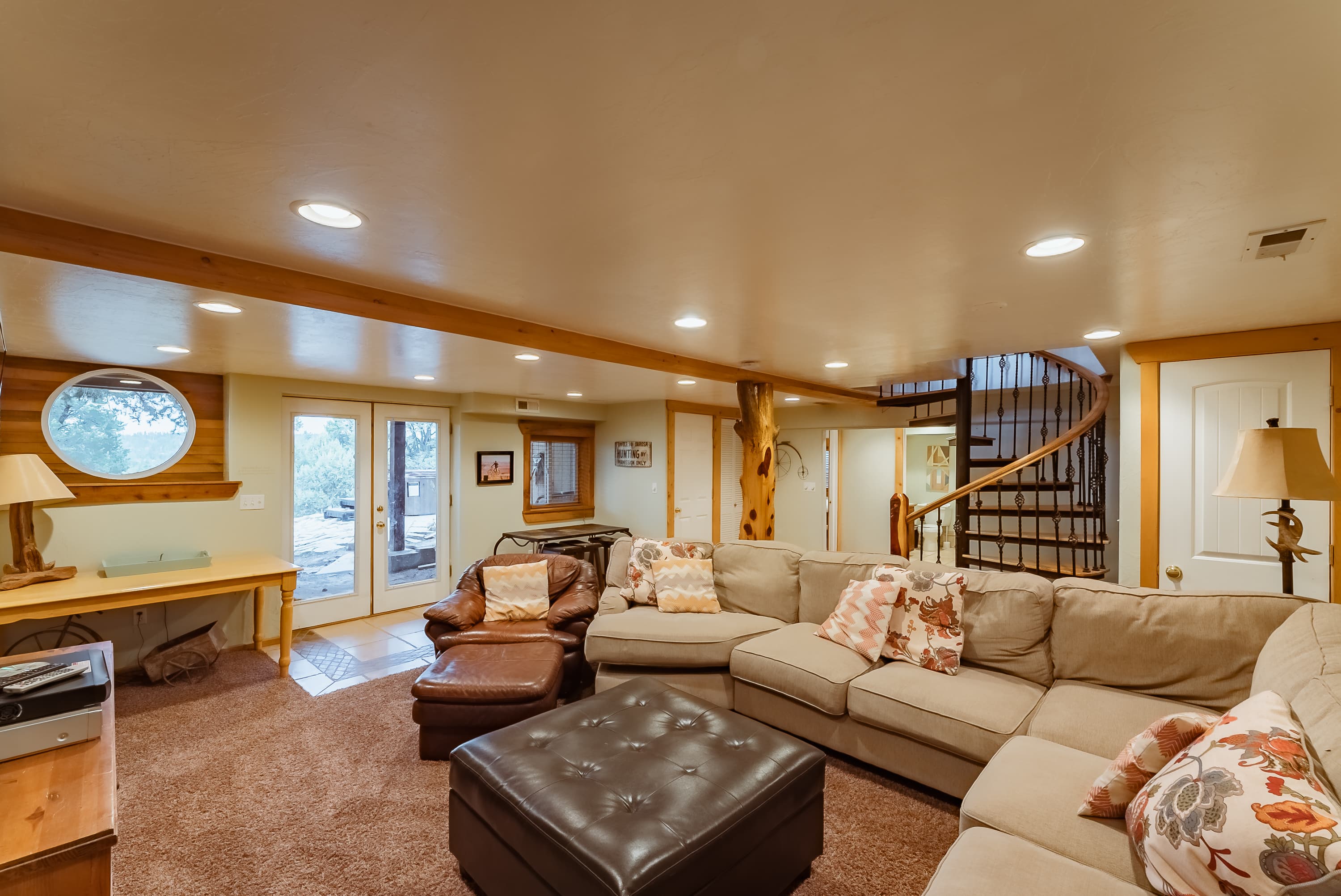 Cozy basement living area featuring a sectional sofa, coffee table, and a staircase.