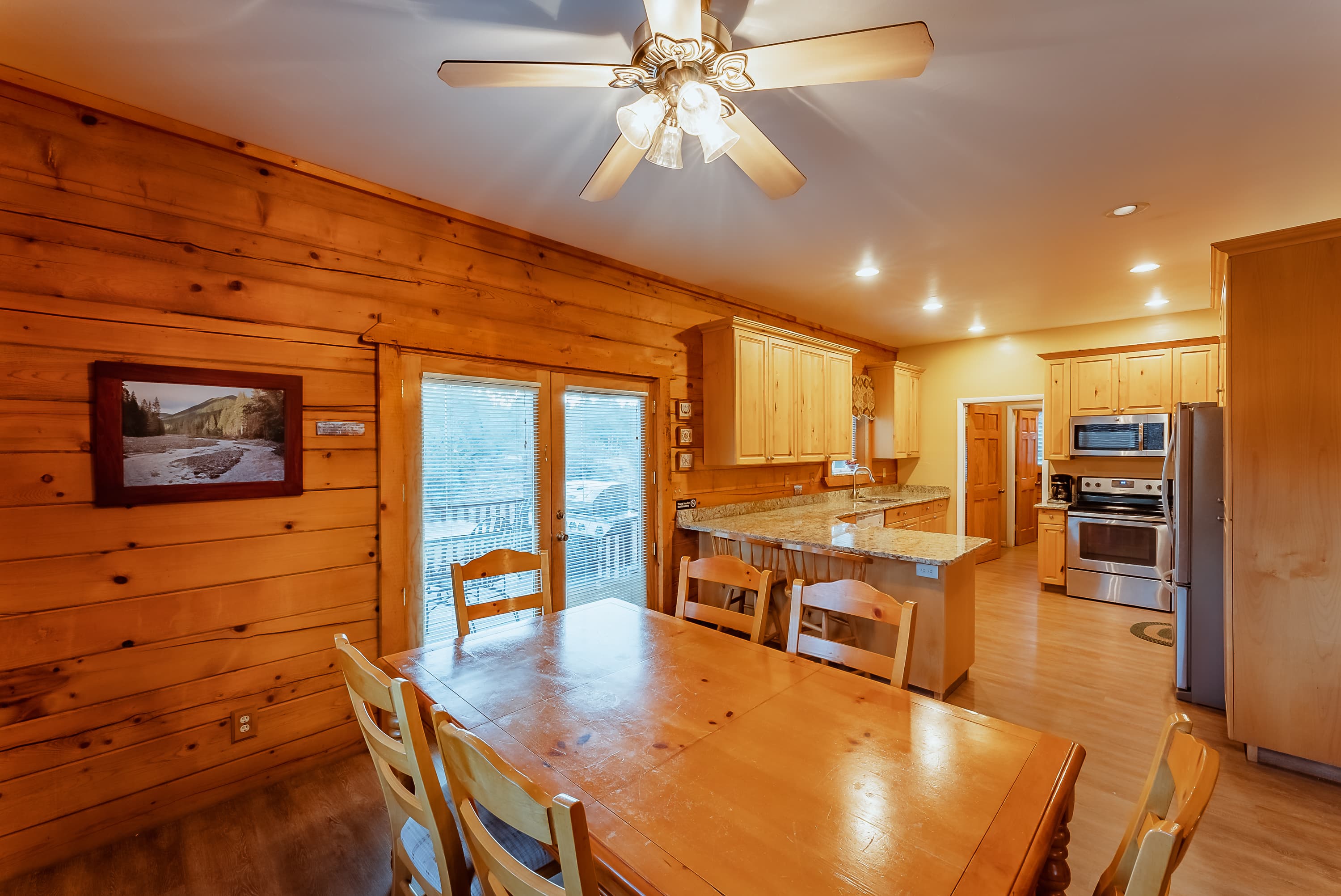Cozy kitchen and dining area with wooden walls, a large table, and modern appliances.