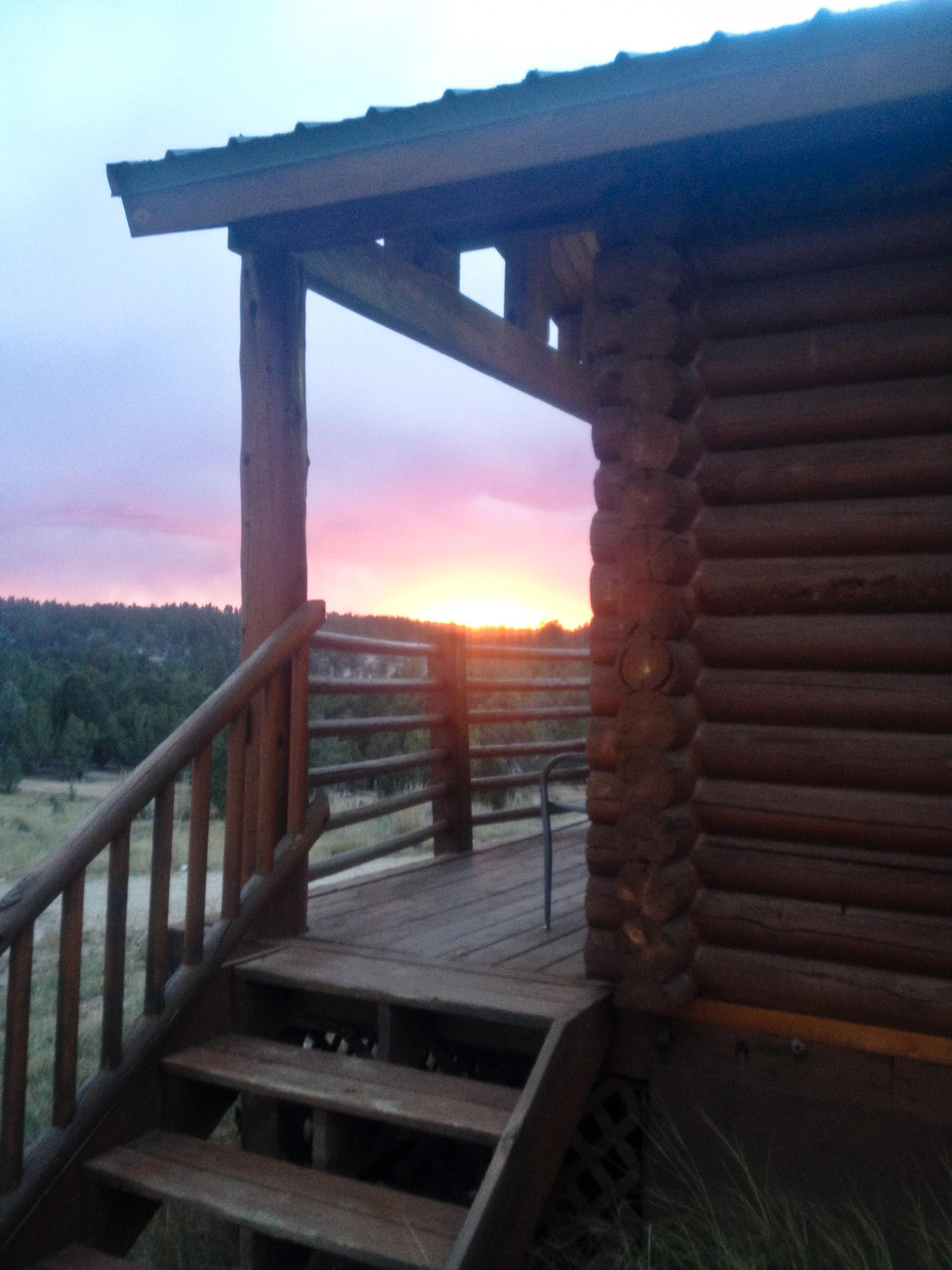 Sunset view from a rustic log cabin porch.