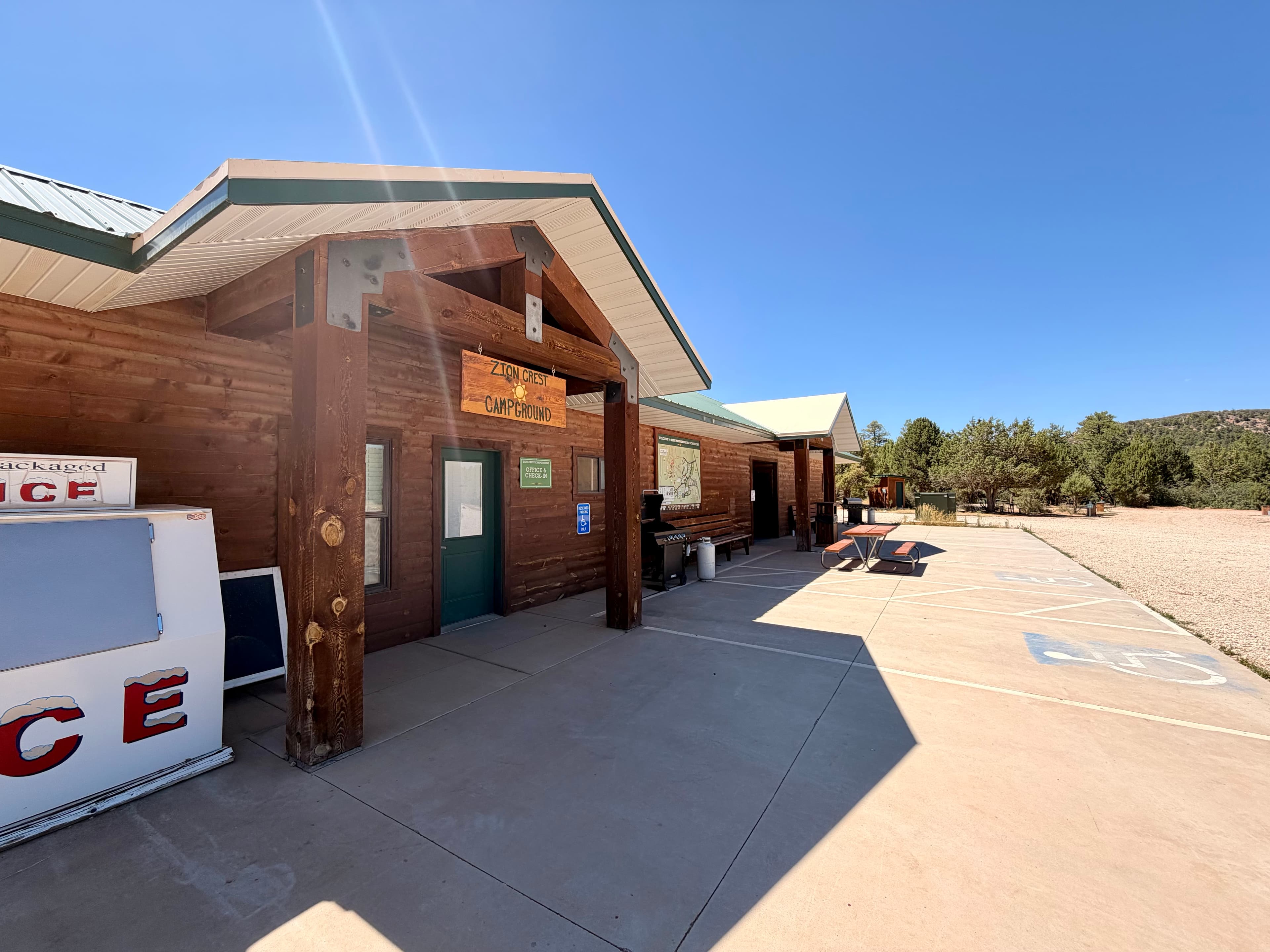 A wooden building labeled "Campground Office" with a clear blue sky and parking area outside.