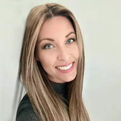 A smiling person with long, straight hair poses against a light background.