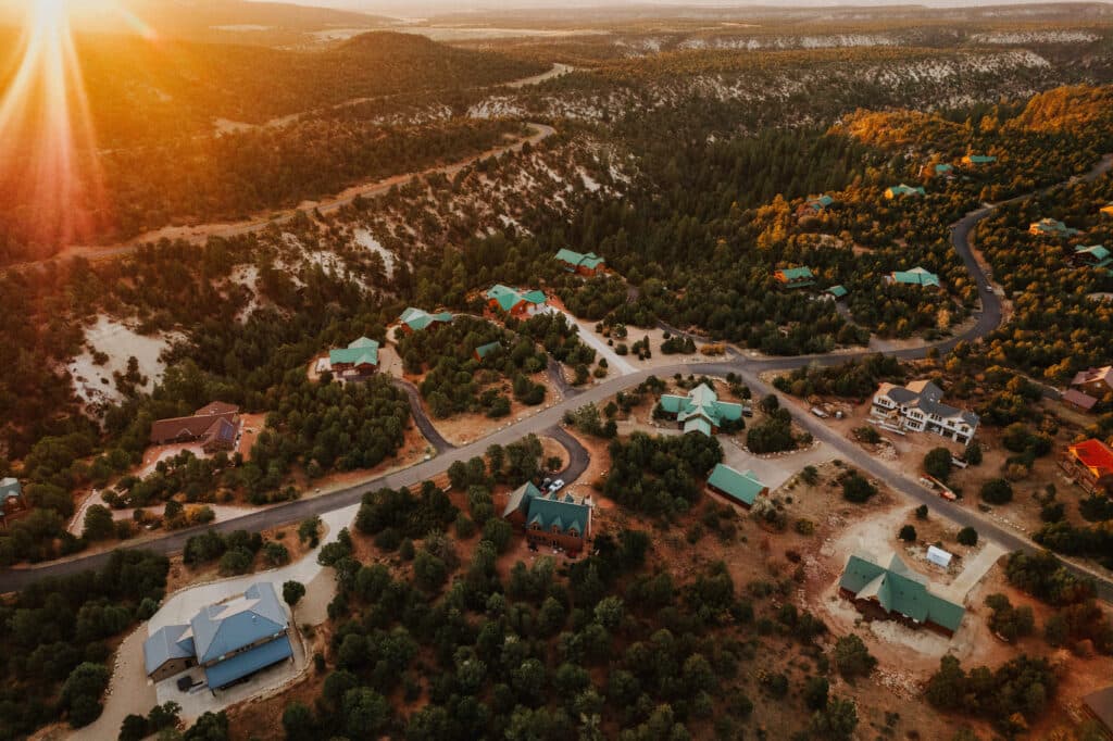 Aerial view of a secluded neighborhood surrounded by wooded hills at sunset.