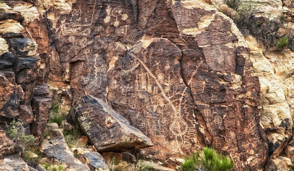 Petroglyphs carved into a rocky surface, depicting abstract shapes and symbols.