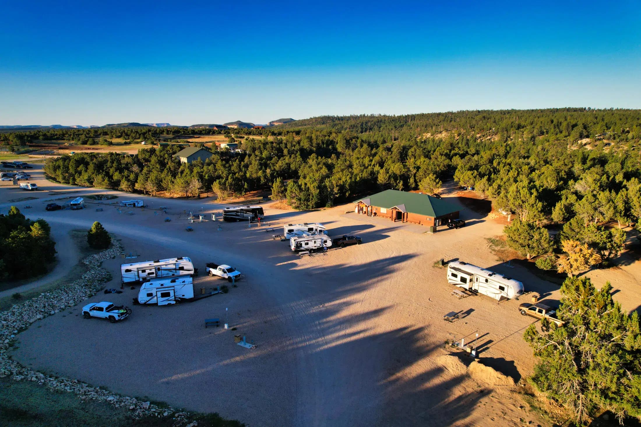 Aerial view of a campground with RVs and a rustic building surrounded by trees.