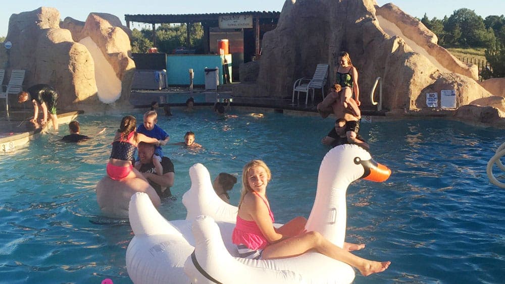 A group of children enjoy a pool party, playing on floaties and interacting in a vibrant pool setting.