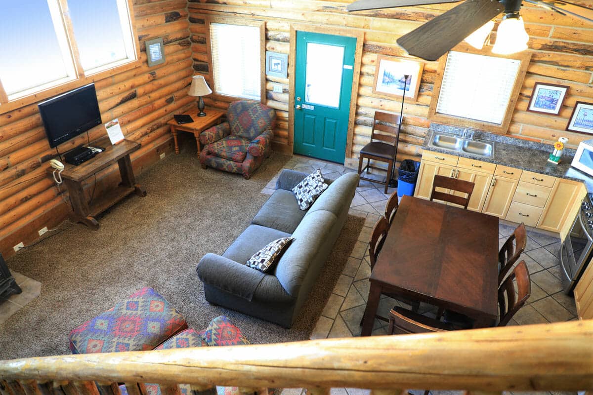 Cozy log cabin living area featuring a sofa, dining table, and green front door.