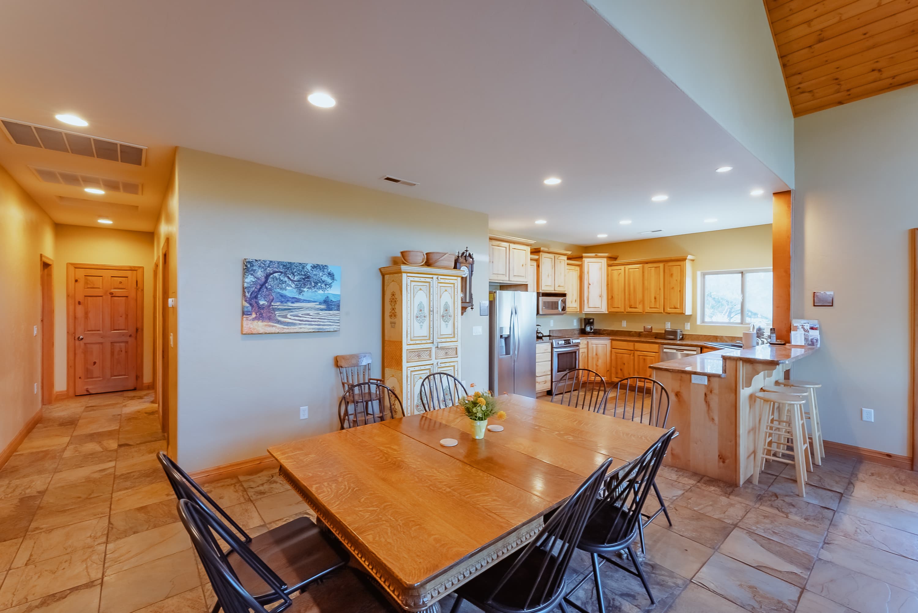 A spacious kitchen and dining area featuring a wooden table, modern appliances, and warm lighting.