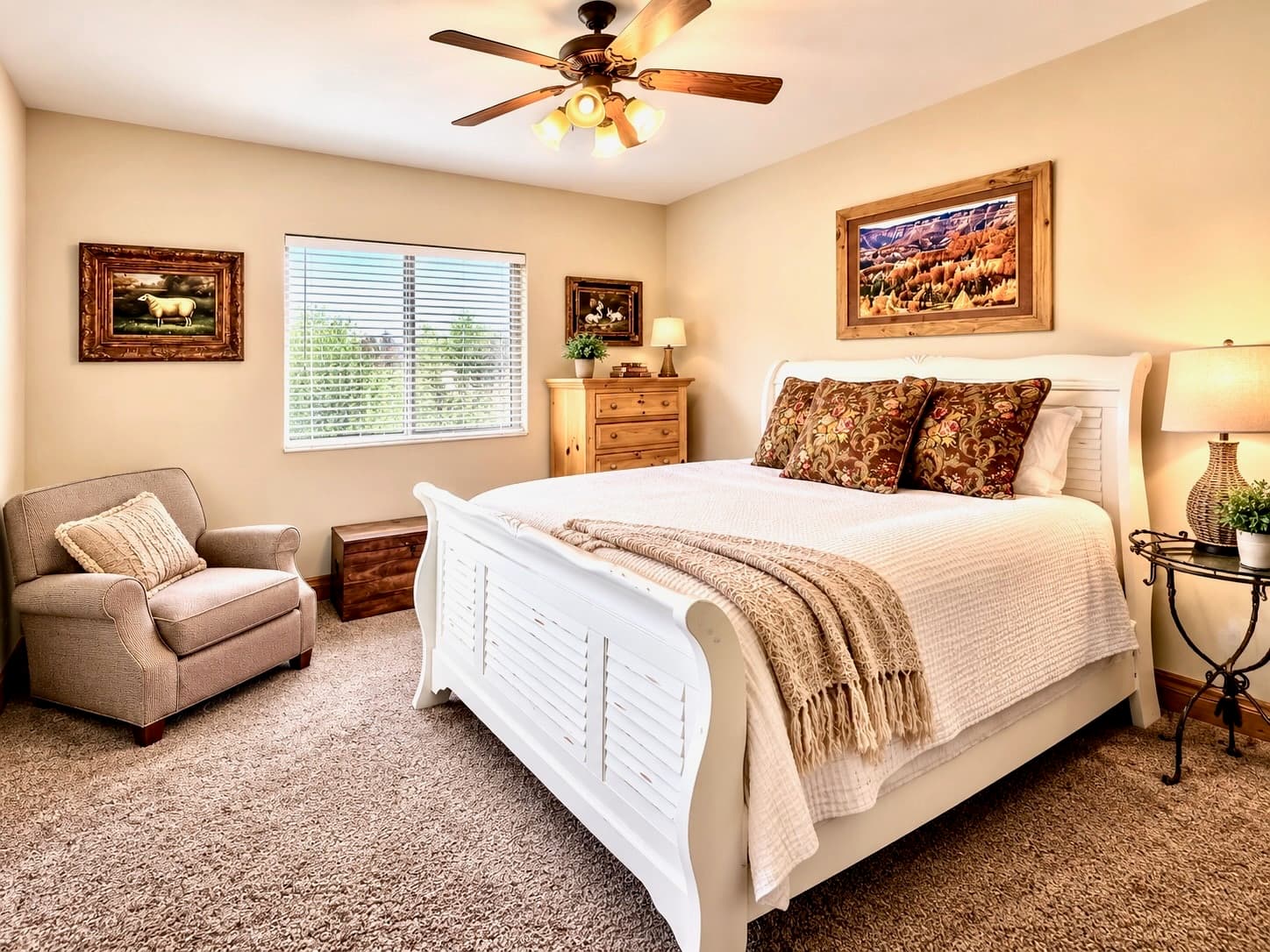 A cozy, well-decorated bedroom featuring a white bed, armchair, and scenic artwork.